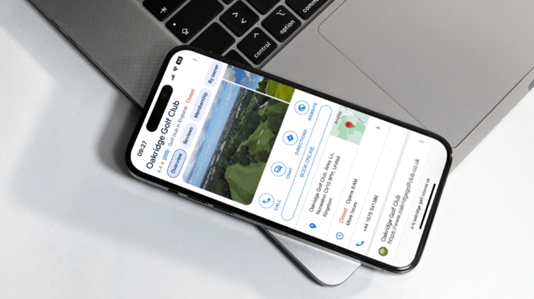 A photo taken of a phone resting on the corner of a laptop, showcasing the Google Business Profile of Oakridge Golf Club.