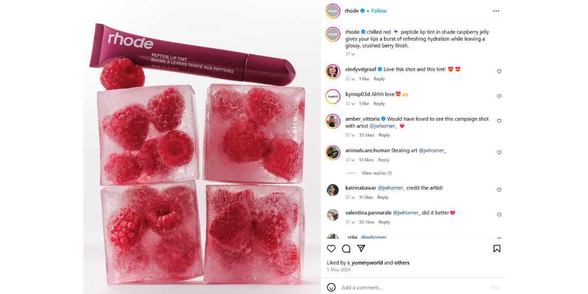 A screenshot taken from Rhode's Instagram of their Peptide Lip Tint product balancing on top of ice cubes filled with raspberries.