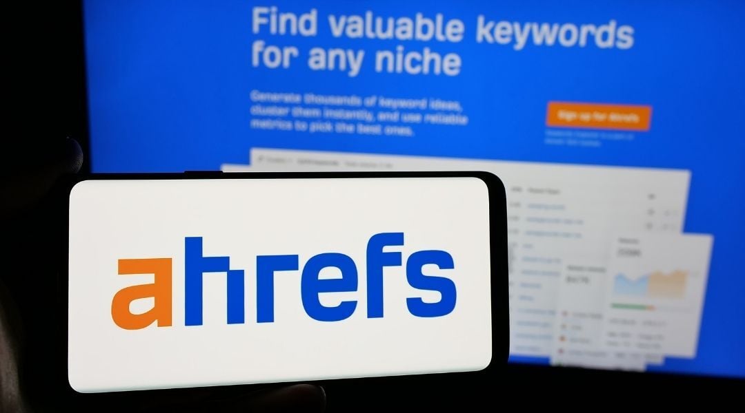 Landscape smartphone screen showing the Ahrefs logo in front of a screen showing the Ahfrefs keyword search page