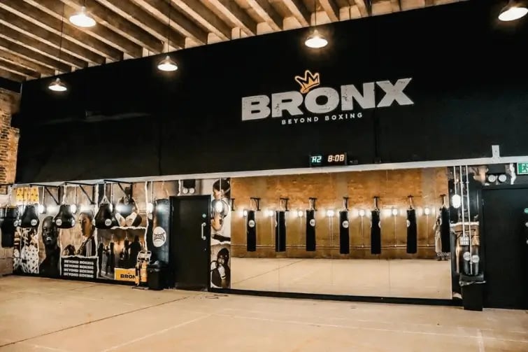 Bronx Boxing Gym in London United Kingdom showing large black banner with bronx's logo above mirrors and punch bags and pictures of Marnie Swindells on the wall