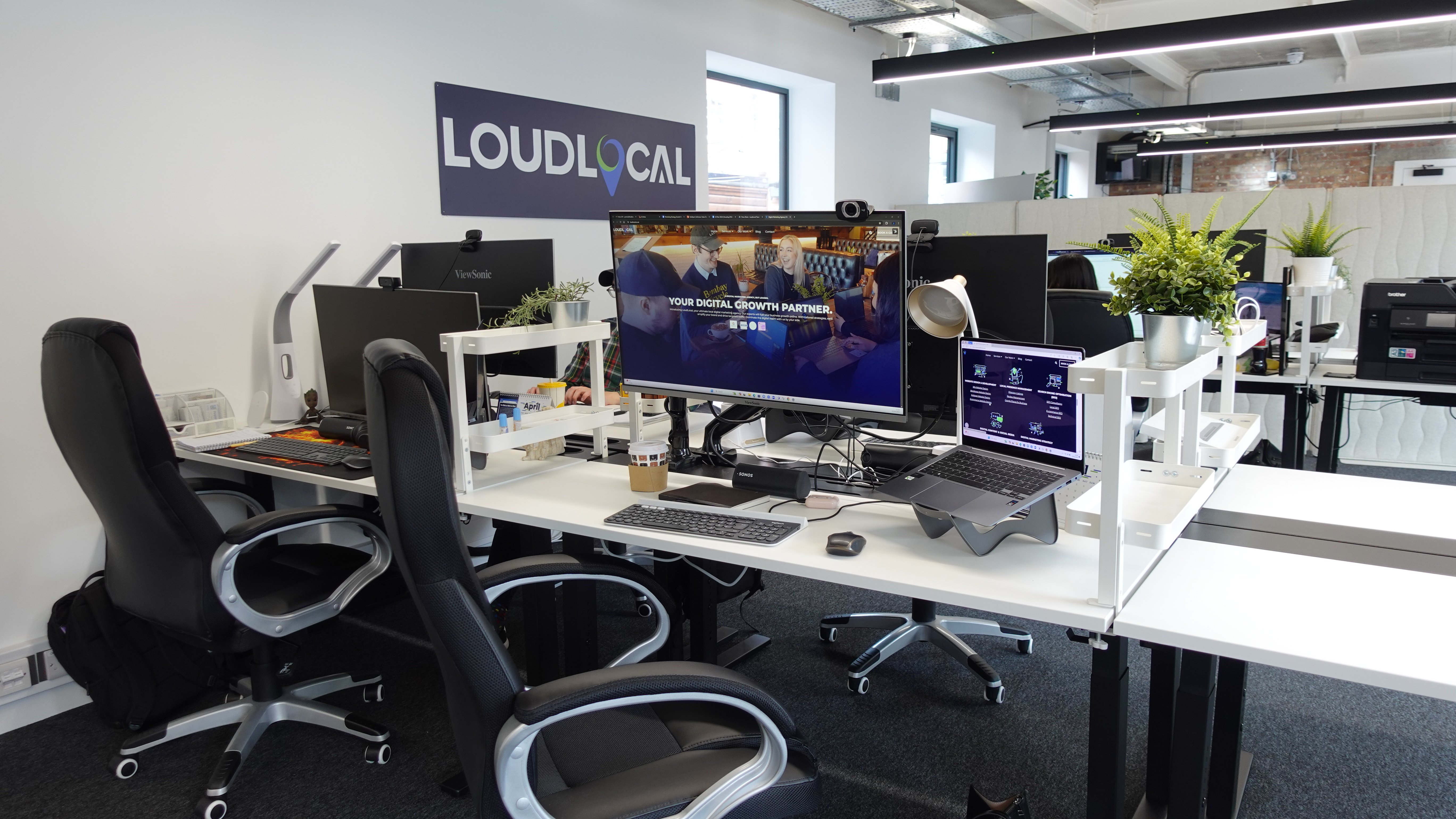 A side profile of our new office shwoing the white desks alongside the loudlocal logo in the background nd. 