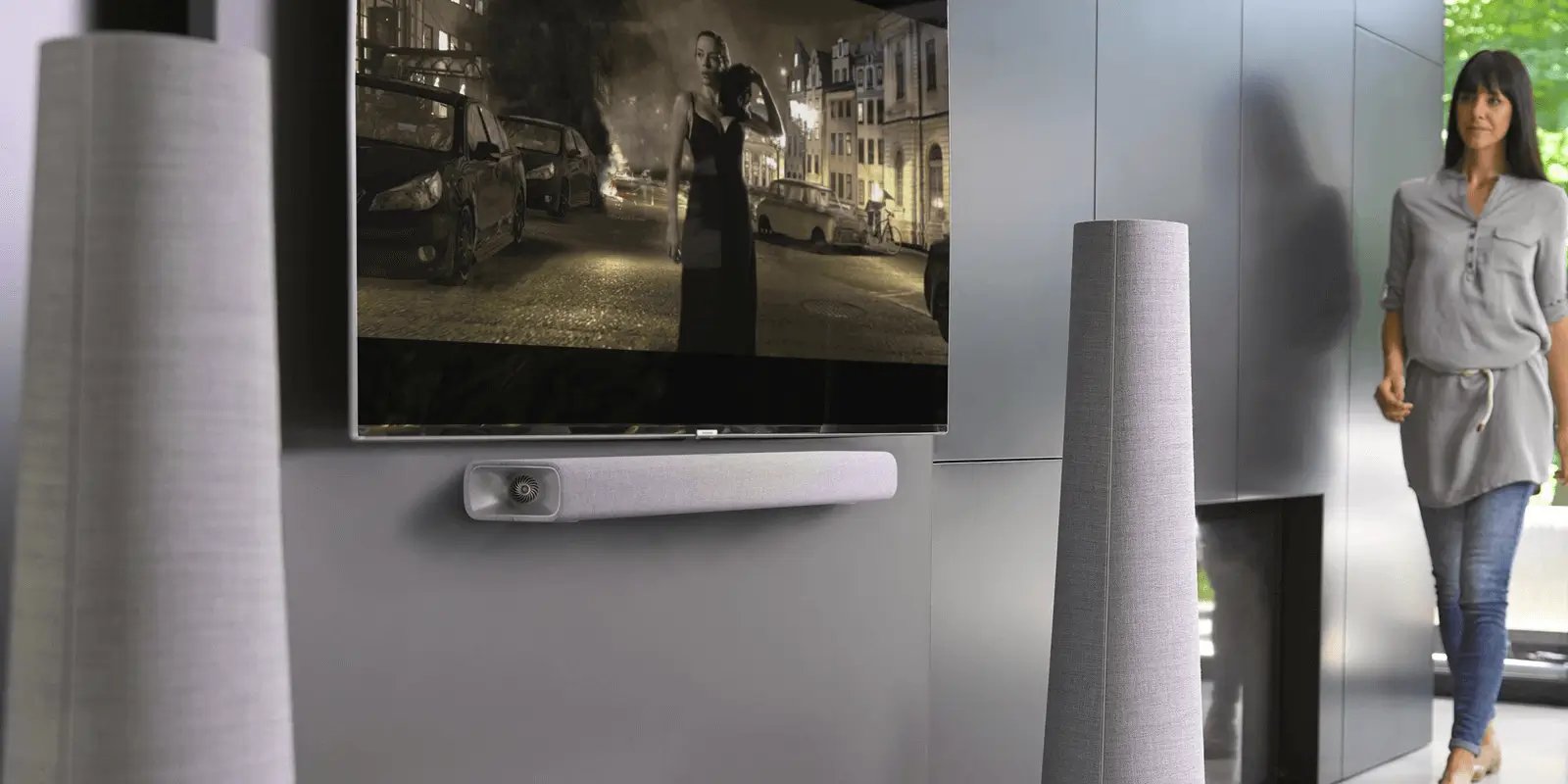This image shows a sound system with a speaker bar below a TV on a grey wall