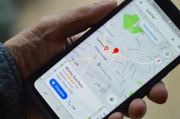 An image of someone holding a phone with Google maps displayed on the screen