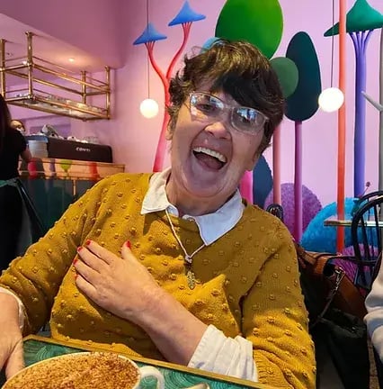 The Action Group is a client of LoudLocal's. This image shows a lady smiling wearing a yellow jumper at one of the Action Group's support centres. 