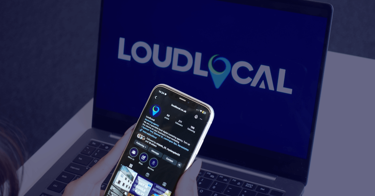 A photo taken of someone holding a phone which is displaying LoudLocal's Instagram profile, as well as a laptop in the background with the 'LoudLocal' logo.