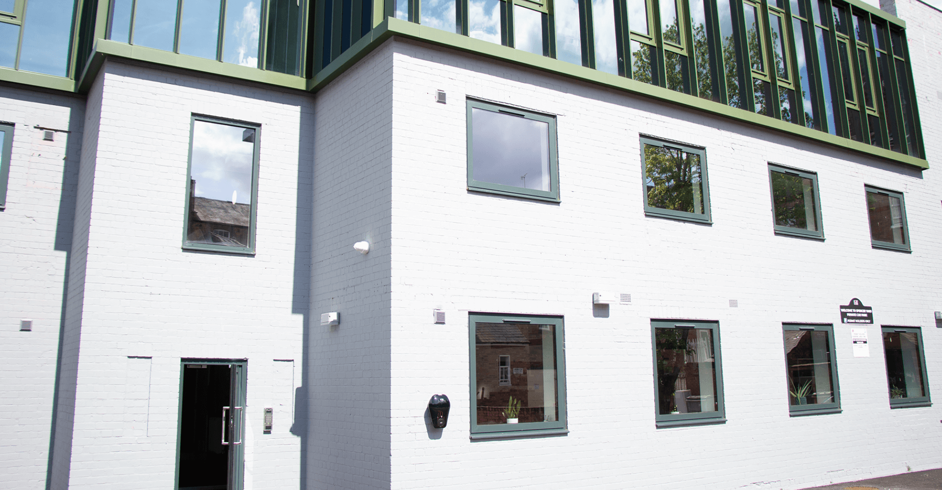 LoudLocals new office in the heart of leamington spa.  The building is grey with green window frames and a door with a matching frame.  It is a sunny day and blue sky can be seen in the background.