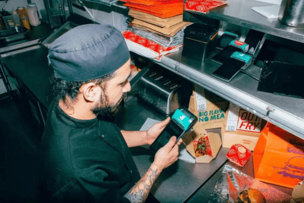 Taster is one of LoudLocal's clients. The image shows someone using a machine to recieve Deliveroo orders at the front of house of one of Taster's franchise.