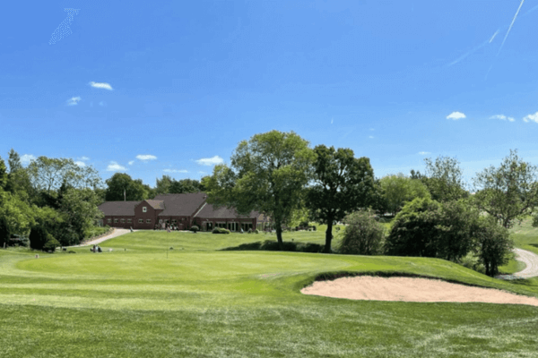 Oakridge golf club is a client of LoudLocal. The image shows the greens at Oakridge with a bunker in the foreground and the club house in the distance. 