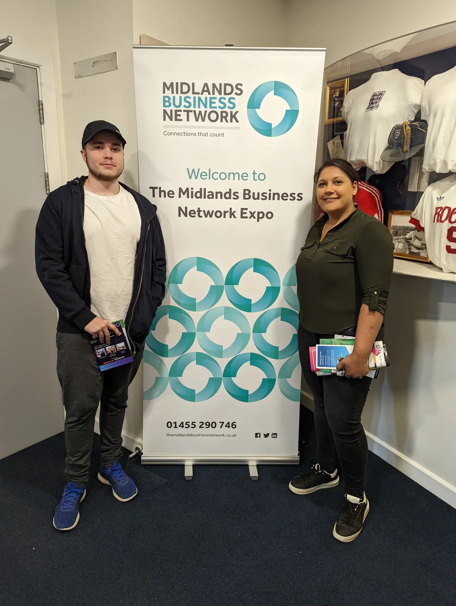 Two LoudLocal colleagues beside a Midlands Business Network Expo banner.