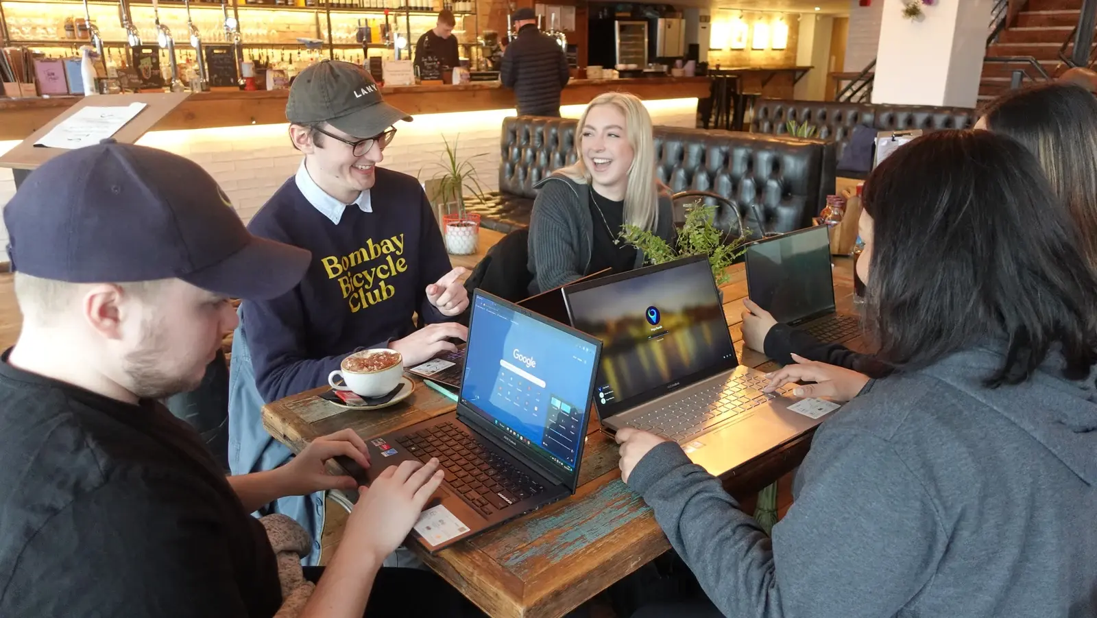 LoudLocal colleagues talking around a café table with laptops and drinks.