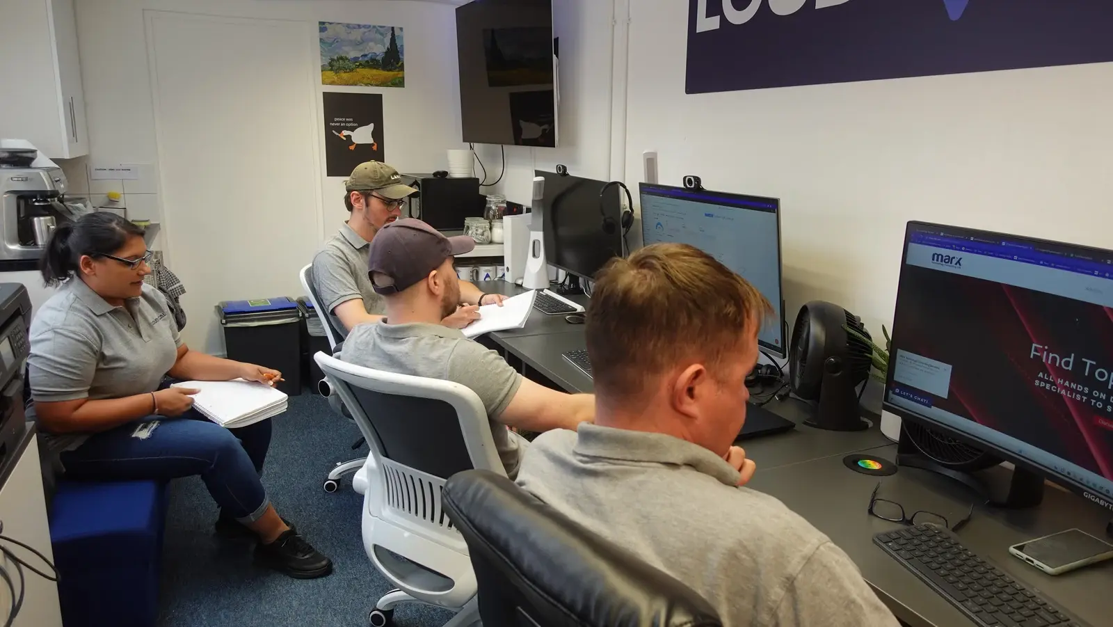 LoudLocal colleagues reviewing work together at their office desks.