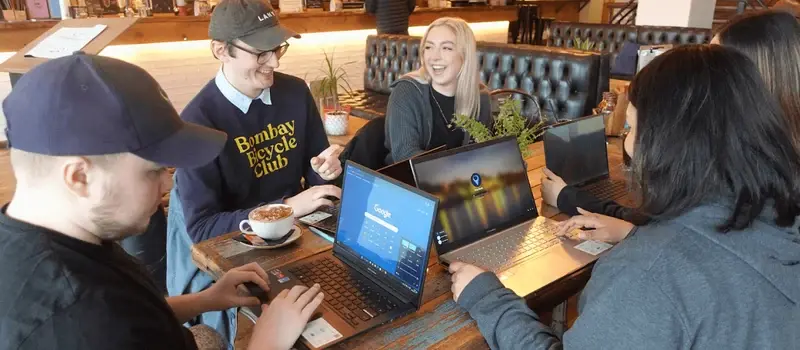 LoudLocal colleagues, including Michael, Taya and Toby, gathered around laptops at a café table during our first team photoshoot.