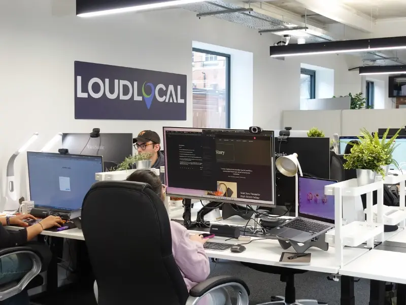 LoudLocal colleagues working at desks with computer screens and plants in the Spencer Yard office in Leamington Spa.