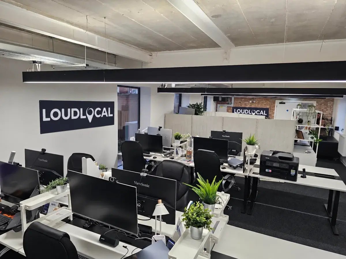 Desks, computer screens and plants in the LoudLocal Leamington Spa office, with LoudLocal signs on the walls.