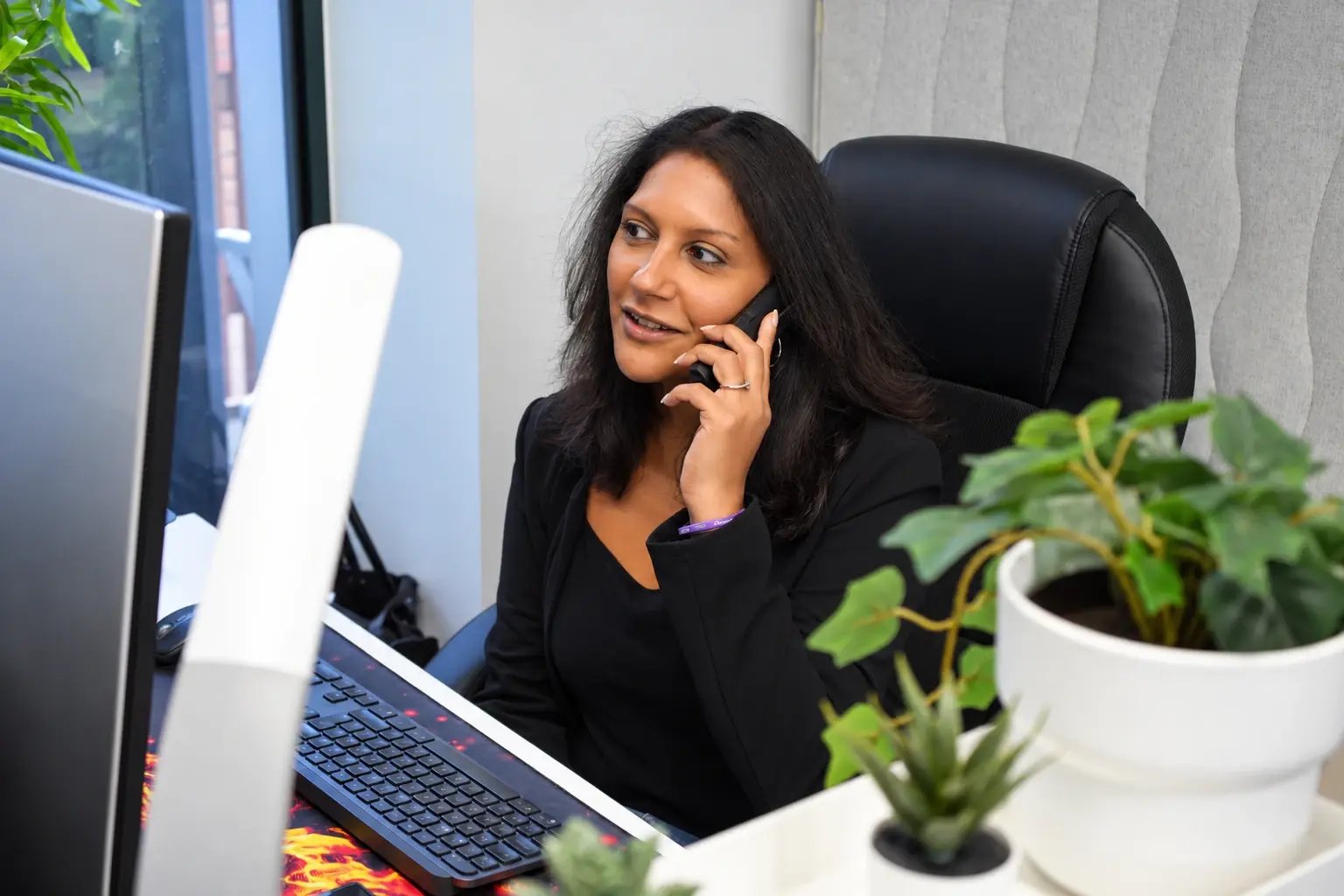 Priya Pandit answering a phone call at her desk.