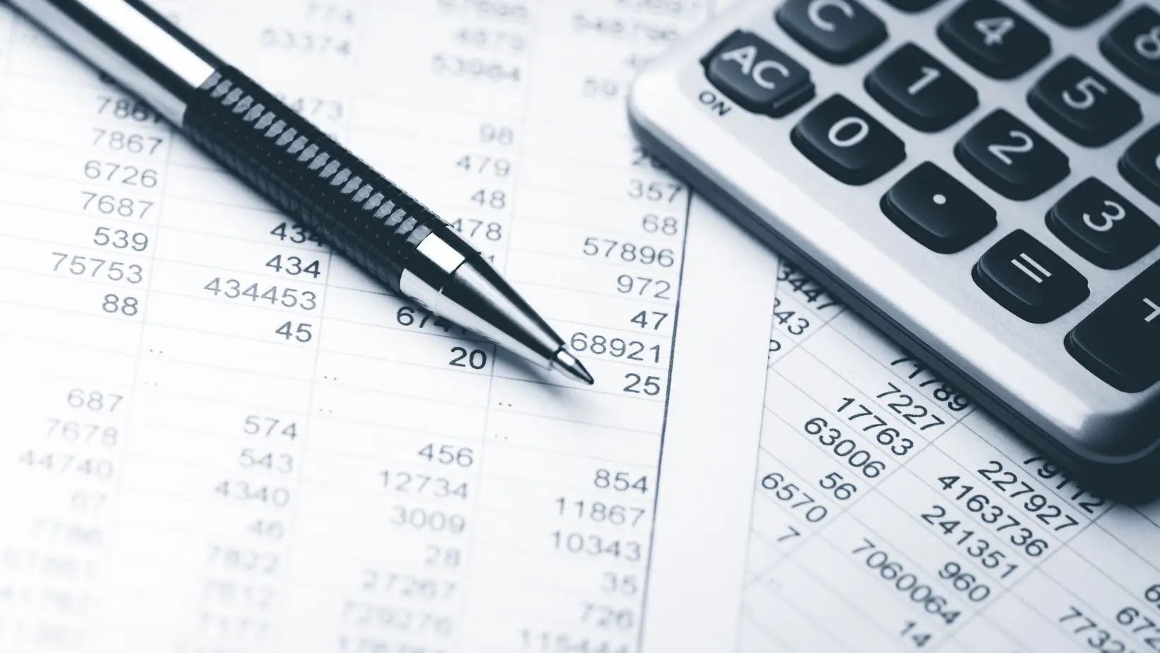 An image of a pen and calculator on top of some spreadsheets of numbers