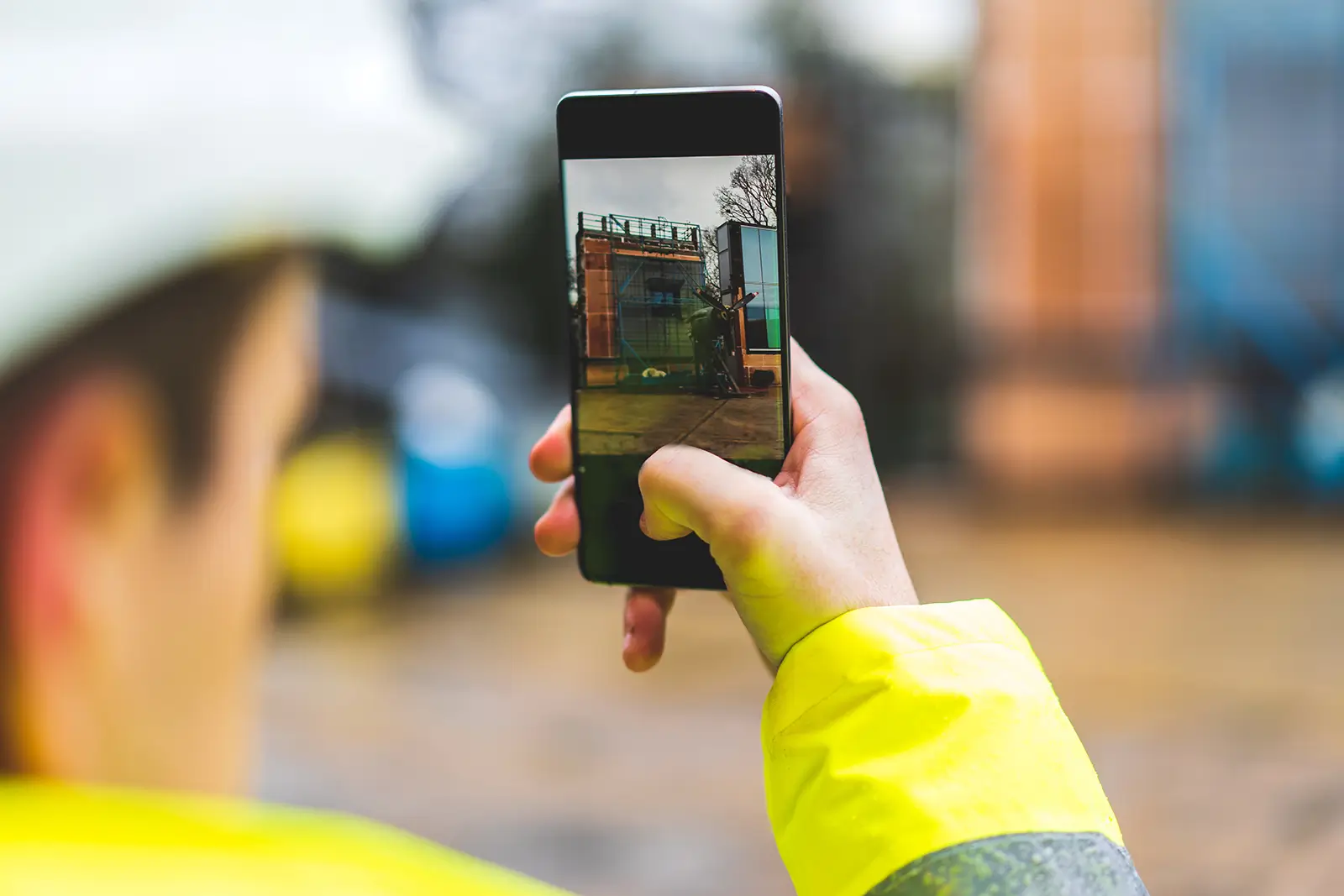 An image of someone wearing hi vis taking a photo on their phone