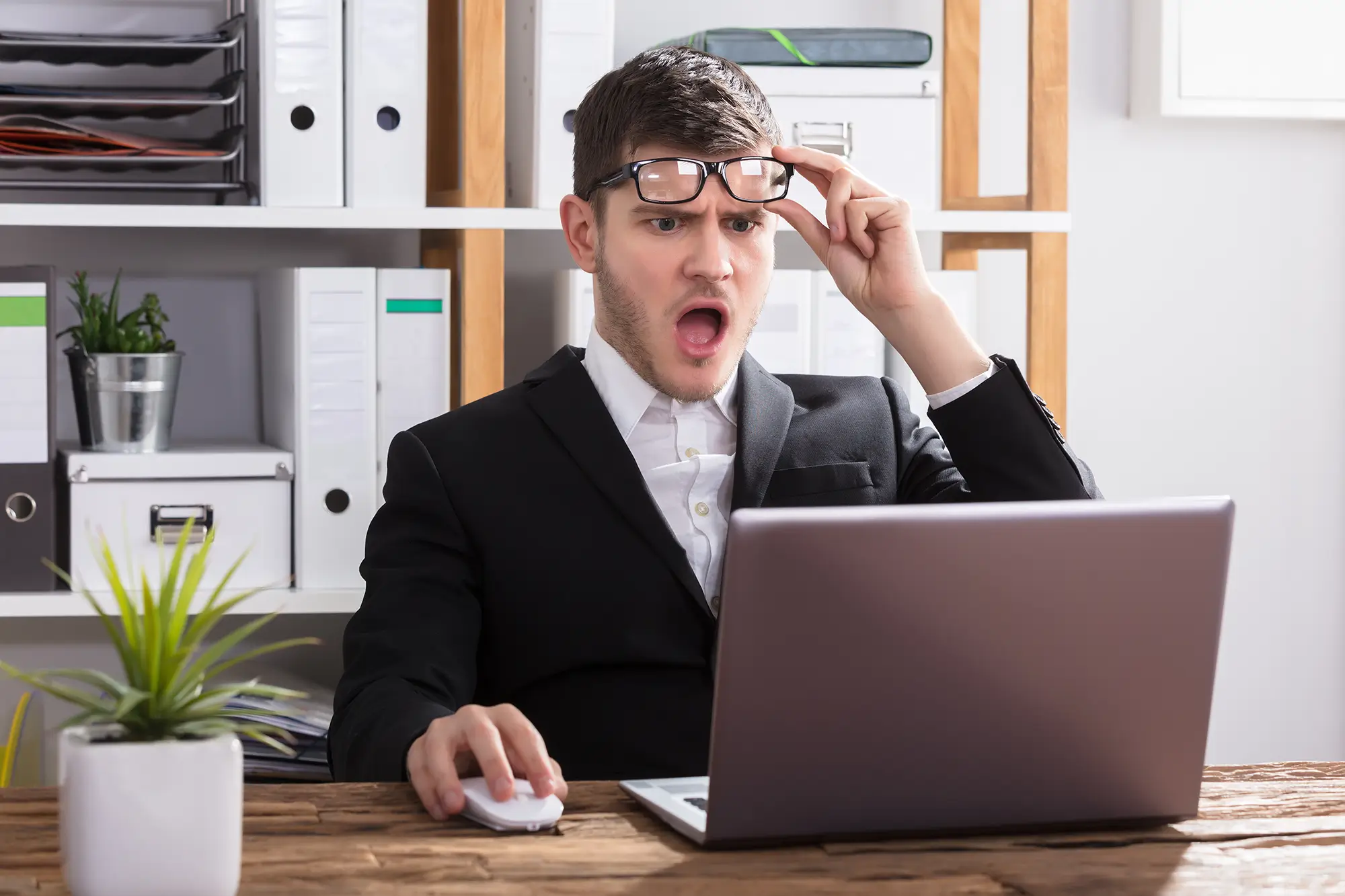An image of a person who seems shocked looking at their laptop
